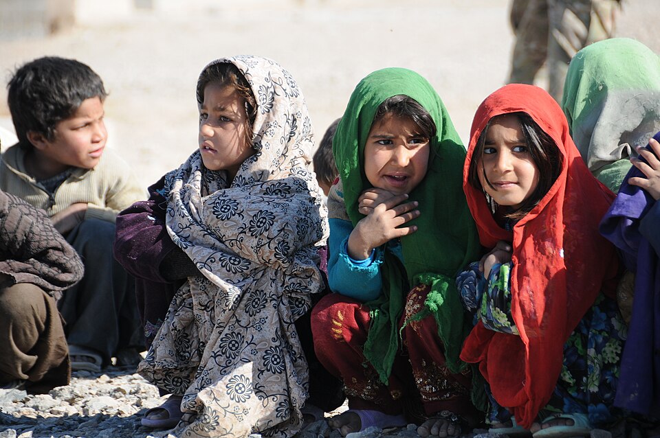 Afghan children watch as U.S. Navy and Army personnel visit a returnee and refugee village near Farah City.